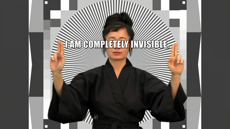 Hito Steyerl diante de um padrão óptico em preto e branco, com a frase I am completely invisible sobre os olhos.