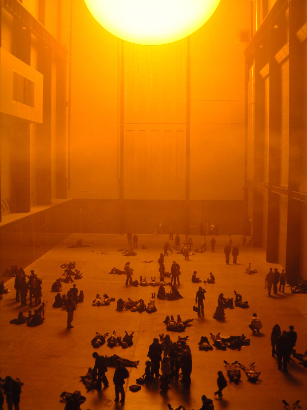 Visitantes reunidos sob o grande sol artificial alaranjado de The Weather Project, na Turbine Hall da Tate Modern.