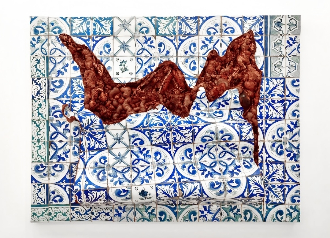 Painel de azulejos portugueses azuis e brancos atravessado por uma grande abertura de matéria vermelha e carnal